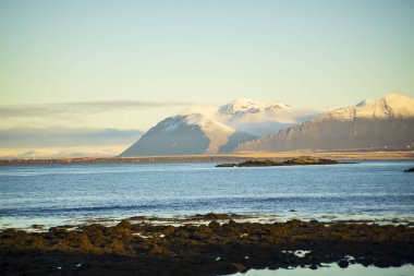 Yumuşak Sabah Işığında Karla kaplı Dağlar ve Rocky Shoreline