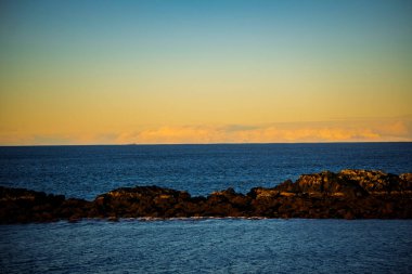 Altın kış denizi ve kayalık kıyı şeridi