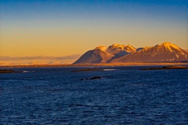 Mavi okyanus dağlarının üzerinde altın gün batımı