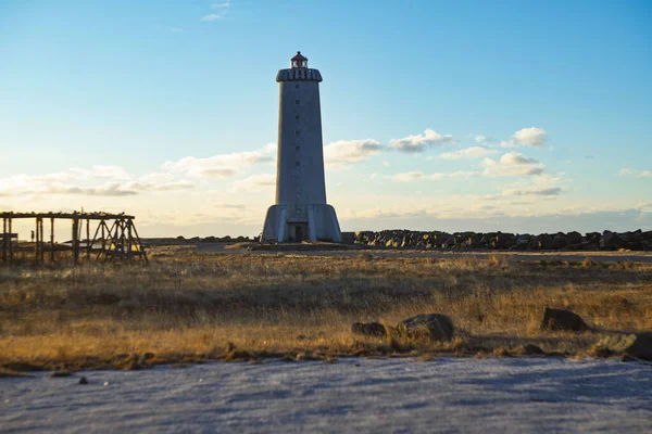 Akranes deniz feneri İzlanda 'da çimenli bir sahilde gün batımında mavi gökyüzünün altında duruyor.