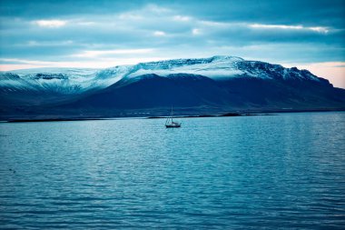 Alacakaranlık 'ta Büyük Okyanus' ta Büyük Okyanus 'ta Büyük Okyanus' a doğru sürüklenen küçük yelkenli Alacakaranlık 'ta karla kaplı dağ sırasına doğru sürükleniyor.