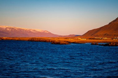 Akranes İzlanda 'nın Sunset' te Karlı Dağlar ve Mavi Deniz manzarası
