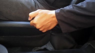 Close-up of a man holding the handbrake while sitting in a car.