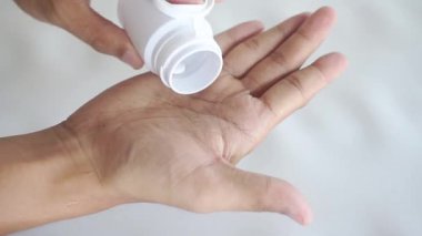 Male hand pouring white medicine tablets from plastic bottle into a palm, antibiotic pills, vitamins, painkillers, isolated on transparent background. healthcare and treatment concept