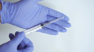 Doktorun elinde mavi eldivenle enjeksiyon yapılan tıbbi şırınga.