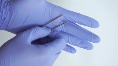 Tıp ve Cerrahi teması: beyaz arka plan üzerinde izole cımbız tutan mavi bir eldiven doktor eli, izole.