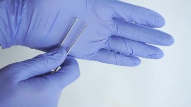 Eldivenli eldiven tutan hassas cımbızlar, klinik ortamda cerrahi aletlerin sergilenmesi, tıbbi prosedürlerdeki doğruluk ve dikkatin önemini vurgulamak