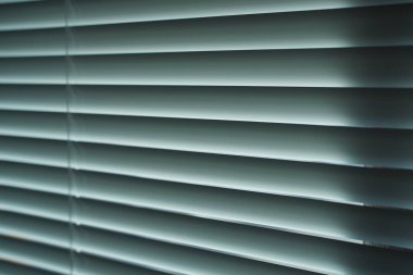 Beyaz Venedik panjurlarının yakın çekim görüntüsü, yatay çizgiler ve gölgeler oluşturarak modern iç mekanlarda gizlilik ve ışık kontrolü sağlar..