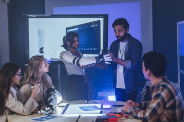 Çeşitli mühendisler ve tasarımcılar yüksek teknoloji yenilik laboratuvarında robotik protez kolun geliştirilmesi konusunda işbirliği yaparlar. Takım çalışması, teknolojik yaratıcılık, insan odaklı ürün tasarımı