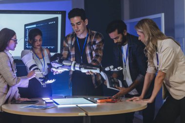 Çeşitli mühendisler ve tasarımcılar yüksek teknoloji yenilik laboratuvarında robotik protez kolun geliştirilmesi konusunda işbirliği yaparlar. Takım çalışması, teknolojik yaratıcılık, insan odaklı ürün tasarımı