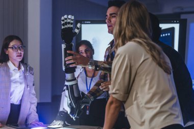 Çeşitli mühendisler ve tasarımcılar yüksek teknoloji yenilik laboratuvarında robotik protez kolun geliştirilmesi konusunda işbirliği yaparlar. Takım çalışması, teknolojik yaratıcılık, insan odaklı ürün tasarımı