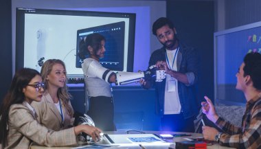 Çeşitli mühendisler ve tasarımcılar yüksek teknoloji yenilik laboratuvarında robotik protez kolun geliştirilmesi konusunda işbirliği yaparlar. Takım çalışması, teknolojik yaratıcılık, insan odaklı ürün tasarımı