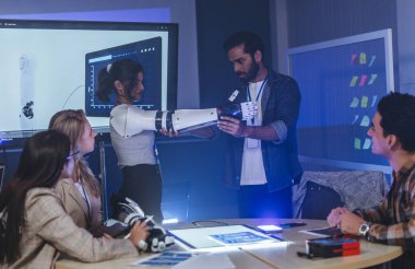 Çeşitli mühendisler ve tasarımcılar yüksek teknoloji yenilik laboratuvarında robotik protez kolun geliştirilmesi konusunda işbirliği yaparlar. Takım çalışması, teknolojik yaratıcılık, insan odaklı ürün tasarımı