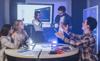 Çeşitli mühendisler ve tasarımcılar yüksek teknoloji yenilik laboratuvarında robotik protez kolun geliştirilmesi konusunda işbirliği yaparlar. Takım çalışması, teknolojik yaratıcılık, insan odaklı ürün tasarımı