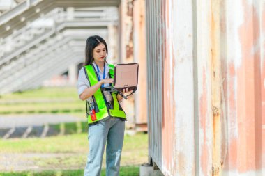 Karışık ırktan bayan teknisyen ofis konteynırlarında saha denetimi yapıyor. Modern işgücünün teknik ve endüstriyel kariyerlerinde, çeşitliliğinde, hassasiyetinde kadınların liderliğini temsil ediyor..