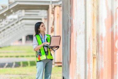 Karışık ırktan bayan teknisyen ofis konteynırlarında saha denetimi yapıyor. Modern işgücünün teknik ve endüstriyel kariyerlerinde, çeşitliliğinde, hassasiyetinde kadınların liderliğini temsil ediyor..