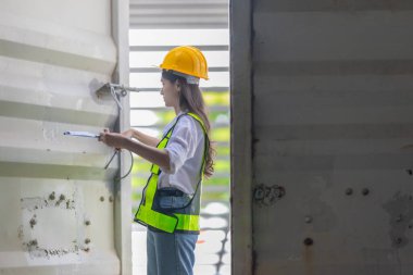 Karışık ırktan bayan teknisyen ofis konteynırlarında saha denetimi yapıyor. Modern işgücünün teknik ve endüstriyel kariyerlerinde, çeşitliliğinde, hassasiyetinde kadınların liderliğini temsil ediyor..