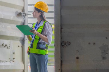 Karışık ırktan bayan teknisyen ofis konteynırlarında saha denetimi yapıyor. Modern işgücünün teknik ve endüstriyel kariyerlerinde, çeşitliliğinde, hassasiyetinde kadınların liderliğini temsil ediyor..