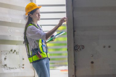 Karışık ırktan bayan teknisyen ofis konteynırlarında saha denetimi yapıyor. Modern işgücünün teknik ve endüstriyel kariyerlerinde, çeşitliliğinde, hassasiyetinde kadınların liderliğini temsil ediyor..