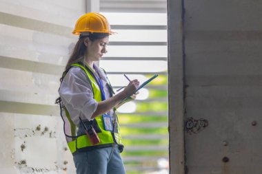 Karışık ırktan bayan teknisyen ofis konteynırlarında saha denetimi yapıyor. Modern işgücünün teknik ve endüstriyel kariyerlerinde, çeşitliliğinde, hassasiyetinde kadınların liderliğini temsil ediyor..