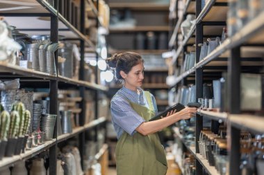Aile şirketinde çalışan bir kız, iyi organize edilmiş bir depoda bulunan el bilgisayarlı bir tarayıcıyla perakende ve toptan satış işlemleri için verimli hisse senedi kontrolü yaptığını doğruladı.