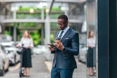 İki iş arkadaşı elektrikli bir scooterla şehir boyunca gidip geliyor, parlak cam binalar arasında ofise doğru gidiyor ve modern, çevre dostu bir iş kültürü sergiliyor..