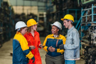 Sert şapkalı çeşitli endüstriyel işçiler, bir otomobil parçaları deposunun içinde, takım çalışmasını, iletişimini ve morali ön plana çıkararak sohbet eder ve birlikte yürürler..