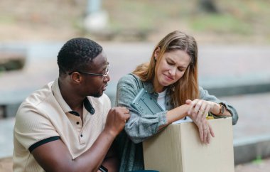 Kadın çalışan bir kutu ofis eşyası taşırken, Afrikalı erkek çalışan onu dışarıda cesaretlendiriyor. Ekonomik kriz ve işyeri desteği ve dayanıklılığı sırasında iş kaybının yansıtılması