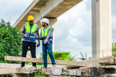 Demiryolu mühendisi ve teknisyeni, beton iskele segmentleri ve inşaat atığı üzerinde kalite kontrol materyali teftişi yapıyor. Ev idaresi ve varlık yeniden kullanımı için yapısal durum kontrol ediliyor.