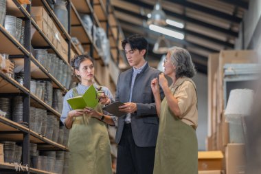 Asyalı bir erkek yatırımcı, ürün turu ve toptan satın alma ve ortaklık fırsatları hakkında iş görüşmesi sırasında iki kadın tarafından yönetilen bir aile seramik deposunu ziyaret ediyor..