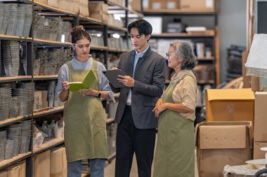 Asyalı bir erkek yatırımcı, ürün turu ve toptan satın alma ve ortaklık fırsatları hakkında iş görüşmesi sırasında iki kadın tarafından yönetilen bir aile seramik deposunu ziyaret ediyor..