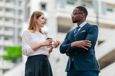 İki iş lideri modern bir ofis kompleksinin dışında odaklanmış bir şirket tartışması yapıyor, CEO düzeyinde bir konuşma, liderlik ve karar verme mekanizması.