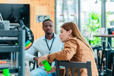 İki ürün tasarımcısı tasarım stüdyosunda 3 boyutlu prototipleri inceleyip tartışıyor. Ürün geliştirmede katkı sağlayan üretim teknolojisi kullanılarak takım çalışmasını, yaratıcılığı ve uygulamalı testleri vurgulamak