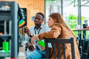 İki ürün tasarımcısı tasarım stüdyosunda 3 boyutlu prototipleri inceleyip tartışıyor. Ürün geliştirmede katkı sağlayan üretim teknolojisi kullanılarak takım çalışmasını, yaratıcılığı ve uygulamalı testleri vurgulamak