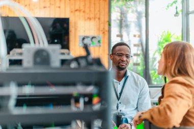 İki ürün tasarımcısı tasarım stüdyosunda 3 boyutlu prototipleri inceleyip tartışıyor. Ürün geliştirmede katkı sağlayan üretim teknolojisi kullanılarak takım çalışmasını, yaratıcılığı ve uygulamalı testleri vurgulamak