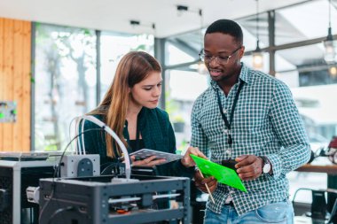 İki ürün tasarımcısı tasarım stüdyosunda 3 boyutlu prototipleri inceleyip tartışıyor. Ürün geliştirmede katkı sağlayan üretim teknolojisi kullanılarak takım çalışmasını, yaratıcılığı ve uygulamalı testleri vurgulamak