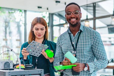 İki ürün tasarımcısı tasarım stüdyosunda 3 boyutlu prototipleri inceleyip tartışıyor. Ürün geliştirmede katkı sağlayan üretim teknolojisi kullanılarak takım çalışmasını, yaratıcılığı ve uygulamalı testleri vurgulamak