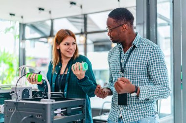 İki ürün tasarımcısı tasarım stüdyosunda 3 boyutlu prototipleri inceleyip tartışıyor. Ürün geliştirmede katkı sağlayan üretim teknolojisi kullanılarak takım çalışmasını, yaratıcılığı ve uygulamalı testleri vurgulamak