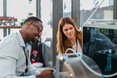 İki ürün tasarımcısı tasarım stüdyosunda 3 boyutlu prototipleri inceleyip tartışıyor. Ürün geliştirmede katkı sağlayan üretim teknolojisi kullanılarak takım çalışmasını, yaratıcılığı ve uygulamalı testleri vurgulamak