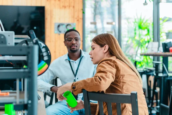 İki ürün tasarımcısı tasarım stüdyosunda 3 boyutlu prototipleri inceleyip tartışıyor. Ürün geliştirmede katkı sağlayan üretim teknolojisi kullanılarak takım çalışmasını, yaratıcılığı ve uygulamalı testleri vurgulamak