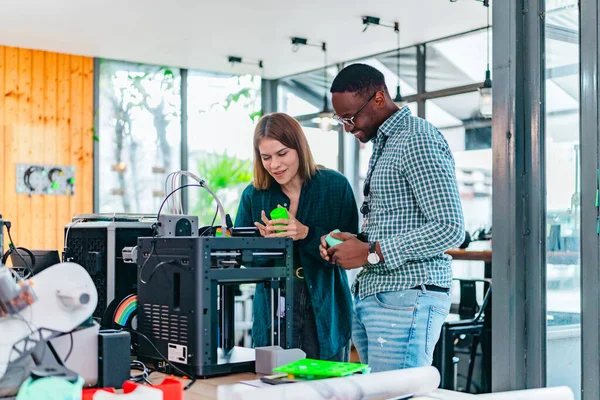 İki ürün tasarımcısı tasarım stüdyosunda 3 boyutlu prototipleri inceleyip tartışıyor. Ürün geliştirmede katkı sağlayan üretim teknolojisi kullanılarak takım çalışmasını, yaratıcılığı ve uygulamalı testleri vurgulamak