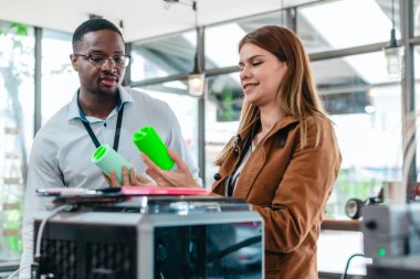 İki ürün tasarımcısı tasarım stüdyosunda 3 boyutlu prototipleri inceleyip tartışıyor. Ürün geliştirmede katkı sağlayan üretim teknolojisi kullanılarak takım çalışmasını, yaratıcılığı ve uygulamalı testleri vurgulamak