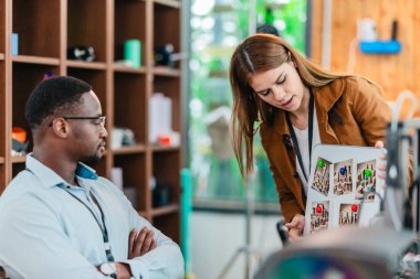 İki ürün tasarımcısı tasarım stüdyosunda 3 boyutlu prototipleri inceleyip tartışıyor. Ürün geliştirmede katkı sağlayan üretim teknolojisi kullanılarak takım çalışmasını, yaratıcılığı ve uygulamalı testleri vurgulamak