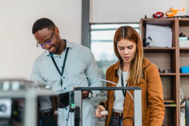 İki ürün tasarımcısı tasarım stüdyosunda 3 boyutlu prototipleri inceleyip tartışıyor. Ürün geliştirmede katkı sağlayan üretim teknolojisi kullanılarak takım çalışmasını, yaratıcılığı ve uygulamalı testleri vurgulamak