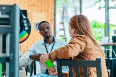 İki ürün tasarımcısı tasarım stüdyosunda 3 boyutlu prototipleri inceleyip tartışıyor. Ürün geliştirmede katkı sağlayan üretim teknolojisi kullanılarak takım çalışmasını, yaratıcılığı ve uygulamalı testleri vurgulamak
