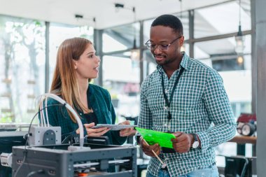 İki ürün tasarımcısı tasarım stüdyosunda 3 boyutlu prototipleri inceleyip tartışıyor. Ürün geliştirmede katkı sağlayan üretim teknolojisi kullanılarak takım çalışmasını, yaratıcılığı ve uygulamalı testleri vurgulamak
