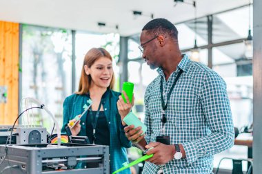 İki ürün tasarımcısı tasarım stüdyosunda 3 boyutlu prototipleri inceleyip tartışıyor. Ürün geliştirmede katkı sağlayan üretim teknolojisi kullanılarak takım çalışmasını, yaratıcılığı ve uygulamalı testleri vurgulamak