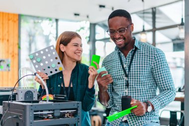 İki ürün tasarımcısı tasarım stüdyosunda 3 boyutlu prototipleri inceleyip tartışıyor. Ürün geliştirmede katkı sağlayan üretim teknolojisi kullanılarak takım çalışmasını, yaratıcılığı ve uygulamalı testleri vurgulamak