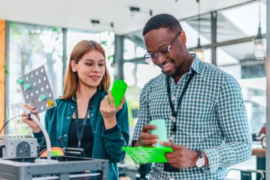 İki ürün tasarımcısı tasarım stüdyosunda 3 boyutlu prototipleri inceleyip tartışıyor. Ürün geliştirmede katkı sağlayan üretim teknolojisi kullanılarak takım çalışmasını, yaratıcılığı ve uygulamalı testleri vurgulamak