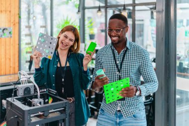 İki ürün tasarımcısı tasarım stüdyosunda 3 boyutlu prototipleri inceleyip tartışıyor. Ürün geliştirmede katkı sağlayan üretim teknolojisi kullanılarak takım çalışmasını, yaratıcılığı ve uygulamalı testleri vurgulamak